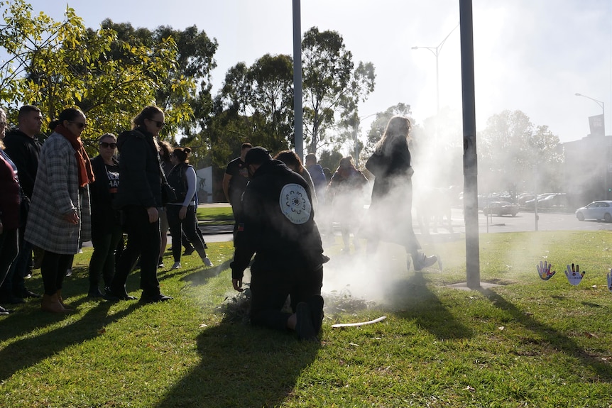 An Aboriginal smoking ceremony being held outside. 
