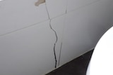 A wide crack low on the interior wall of a house