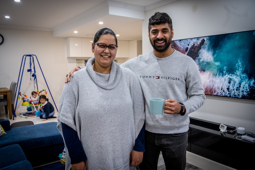 A young couple inside a house, smiling