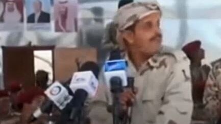 A Yemeni government military member looks up the moment before a drone drops a bomb on a parade.