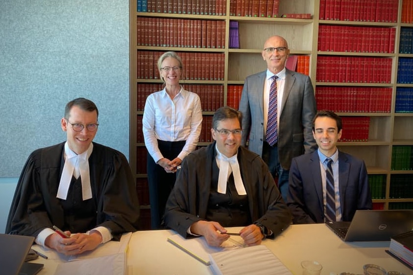A group of lawyers posing in front of a bookshelf