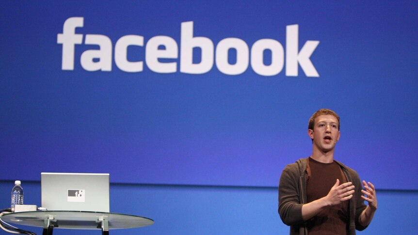 Facebook CEO Mark Zuckerberg talking to an audience with a Facebook sign behind him