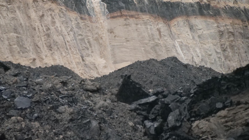 A coal seam behind a pile of coal