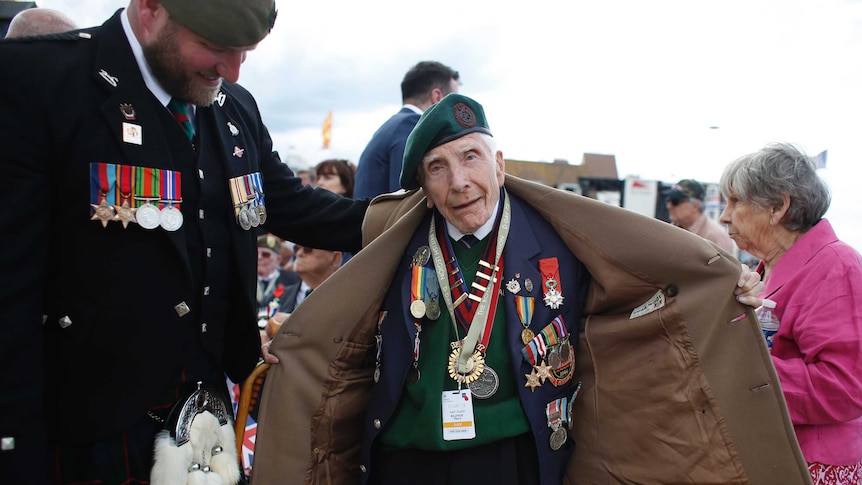 British D-Day veteran Harry Billinge opens his coat to show his medals.