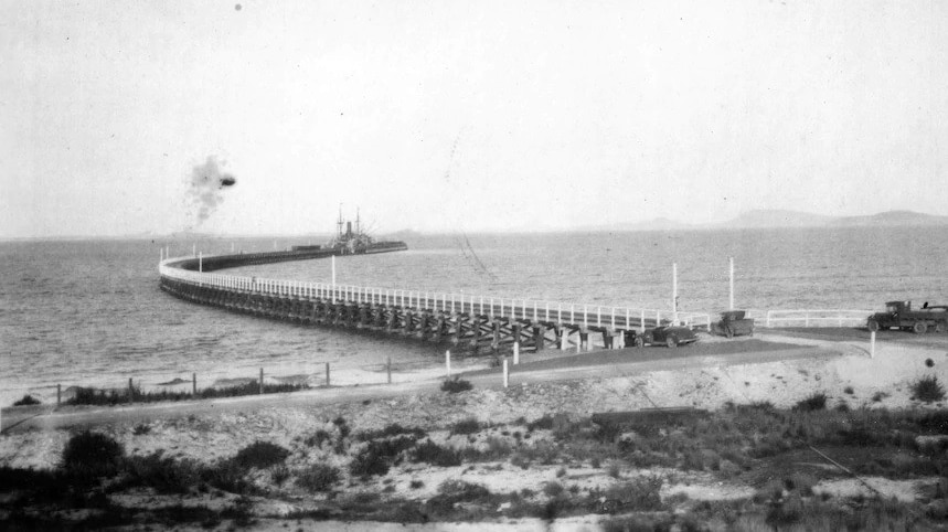 A black and white shot of a curved jetty.