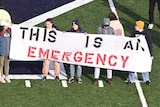 Protesters hold up banners in the middle of a football field