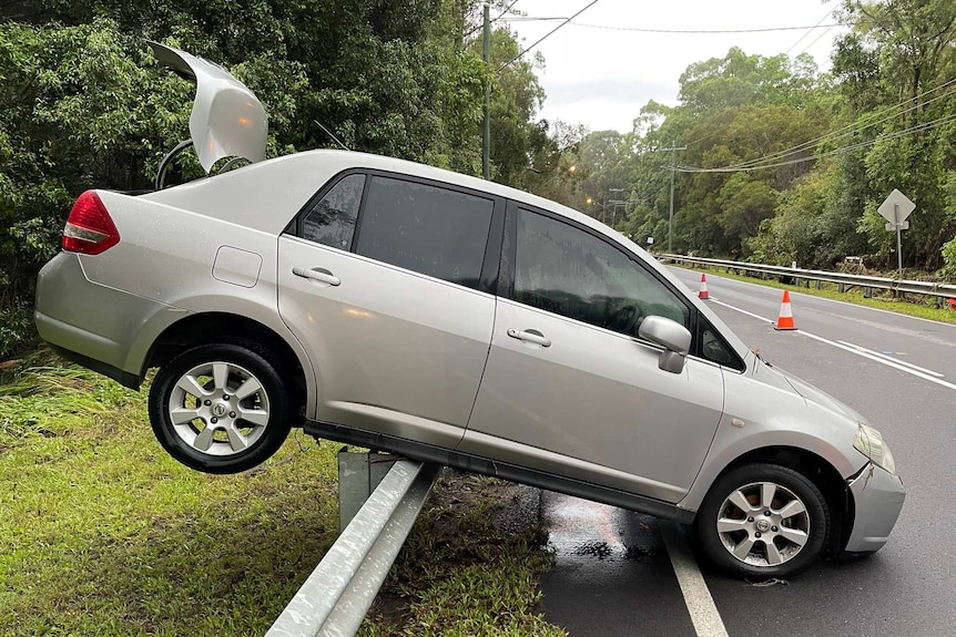 Car lifted onto guard rail on highway.