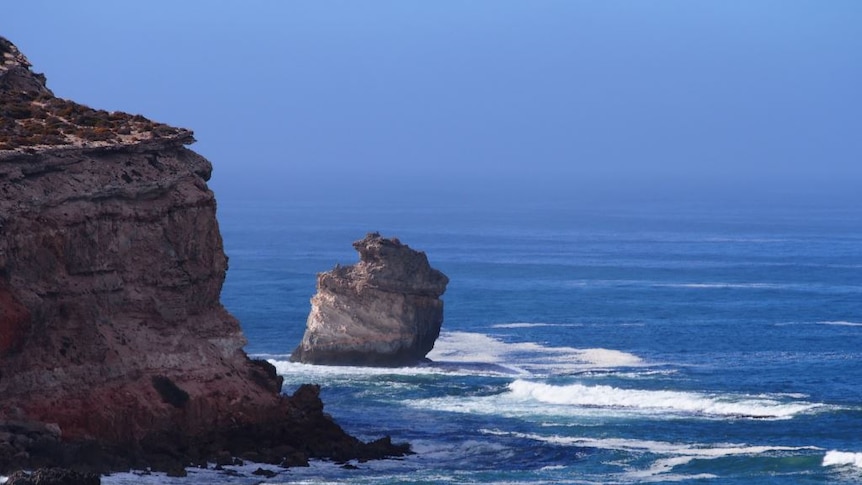 Steep cliffs that drop off to a deep blue ocean.