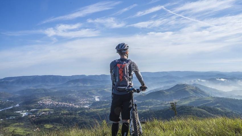 Photo of cyclist on top of a mountain looking out over the landscape 