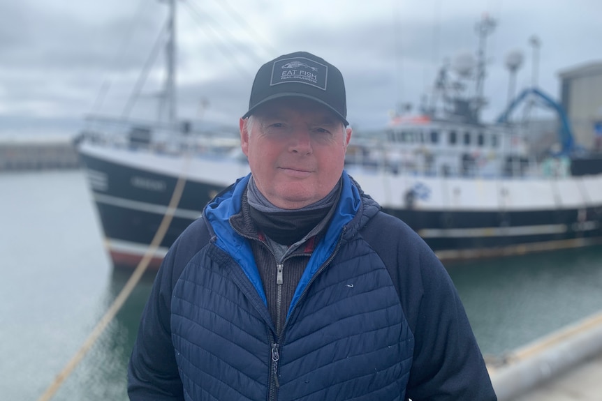  A fisherman in a baseball cap beside a dock in Peterhead.