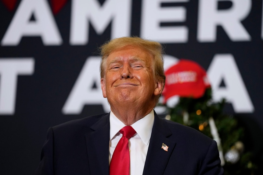 Donald Trump smiles in front of podium 