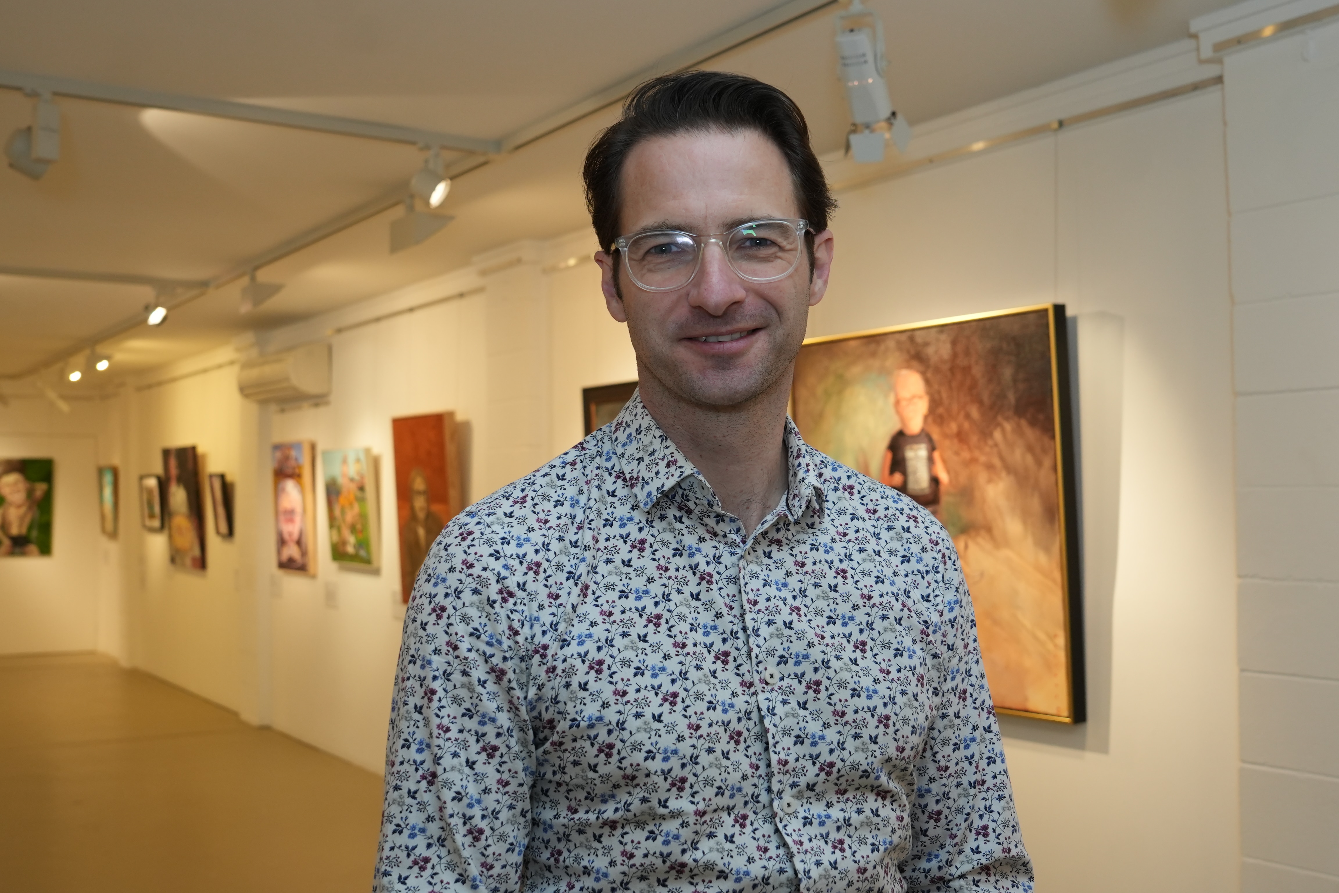 Tim está allí sonriendo, con obras de arte en las paredes detrás de él.