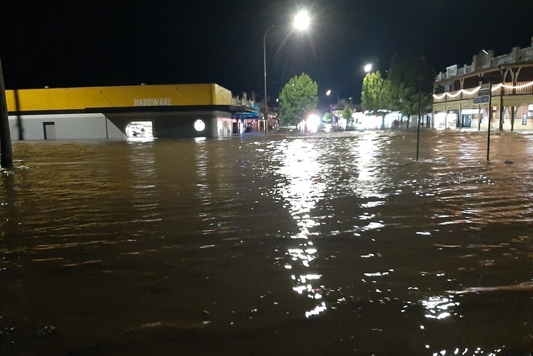 A hardware shop is flooded by brown water in the dark.