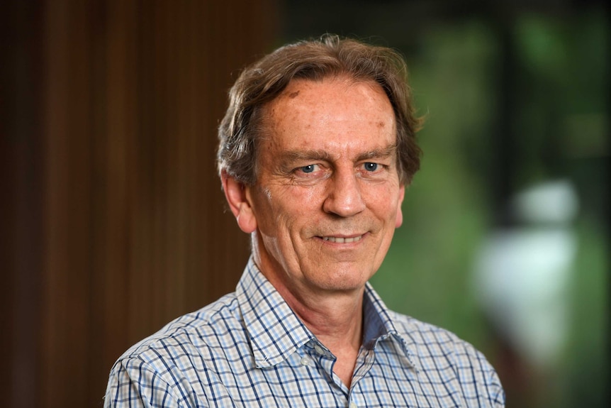 An older man in a checked shirt with brown hair