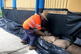 A council worker sandbags a restaurant in Townsville