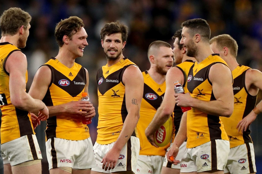 A group of AFL players congratulate each other on a win on a stadium ground