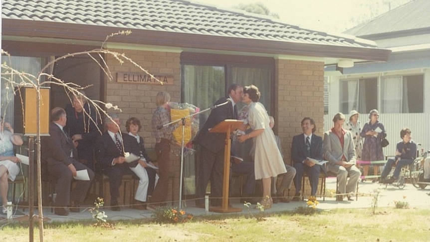 An old photo of a group of people stand and sit in front a brick house. Ausnew Home Care, NDIS registered provider, My Aged Care