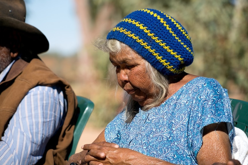 Christabel Swan sits in a blue dress and blue and yellow knitted beanie