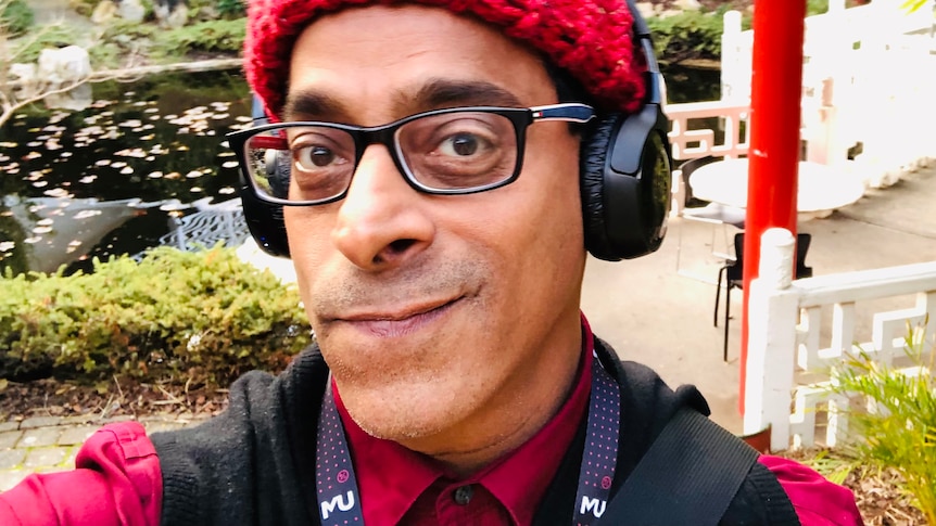 Rahul Gairola wearing a red beanie and headphones in a garden.