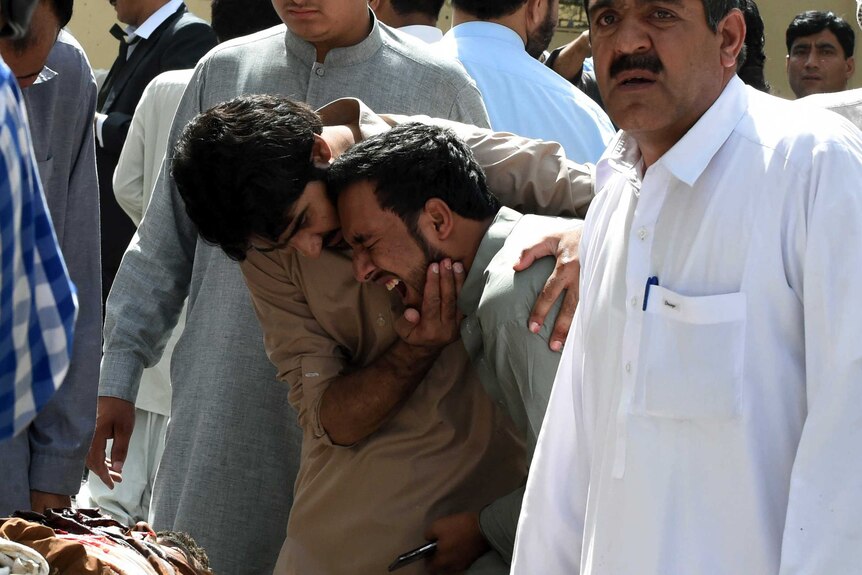 Pakistani local journalists react over the body of a news cameraman after a bomb explosion in Quetta