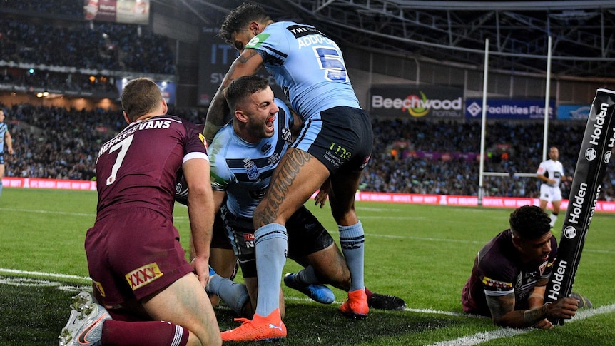 James Tedesco is embraced by a teammate as Queensland players slump to the floor