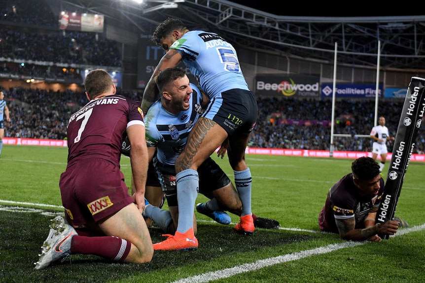 James Tedesco is embraced by a teammate as Queensland players slump to the floor