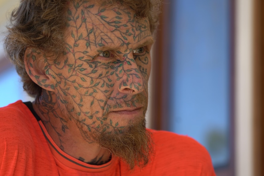 A close up of Jan Van Der Zon who has tattoos of vines on his face.
