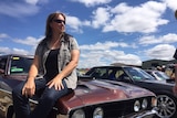 Heather Sherlock sits on the bonnet of her car.