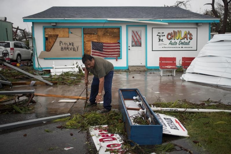 Carlos clears debris from outside his shop