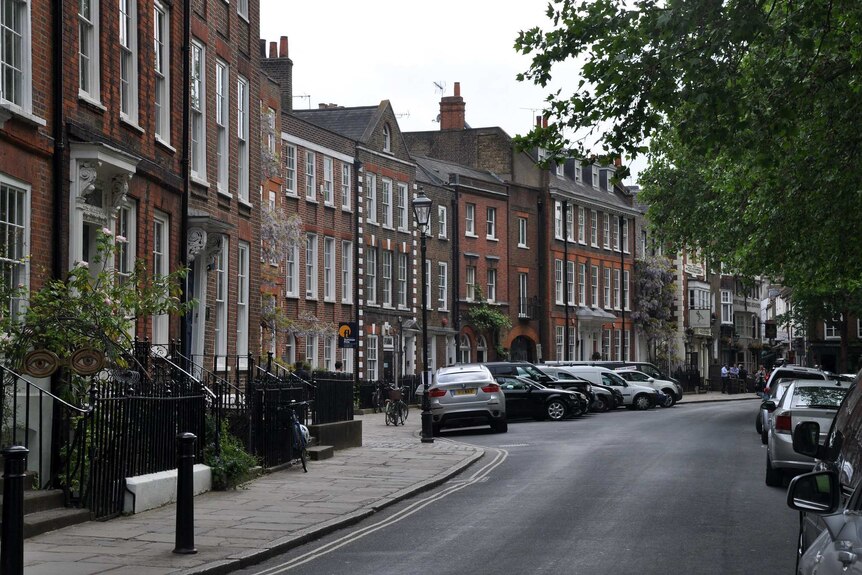 You view an affluent, leafy street in London with rows of Georgian houses.