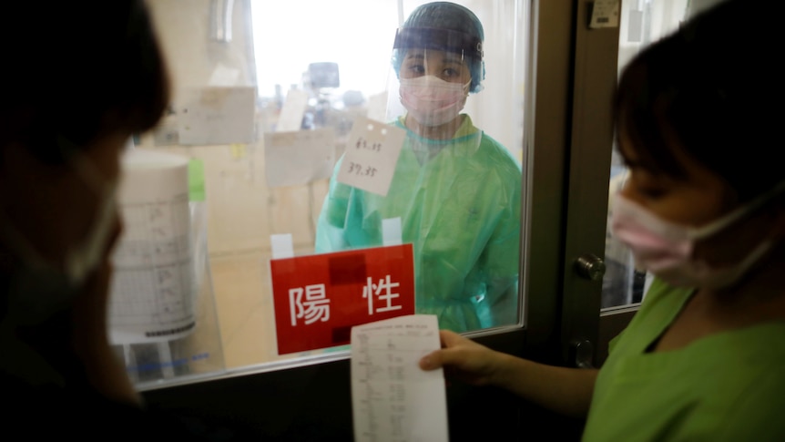 A woman stands behind a glass door with a red sign on it as a person in scrubs holds a piece of paper. Ausnew Home Care, NDIS registered provider, My Aged Care