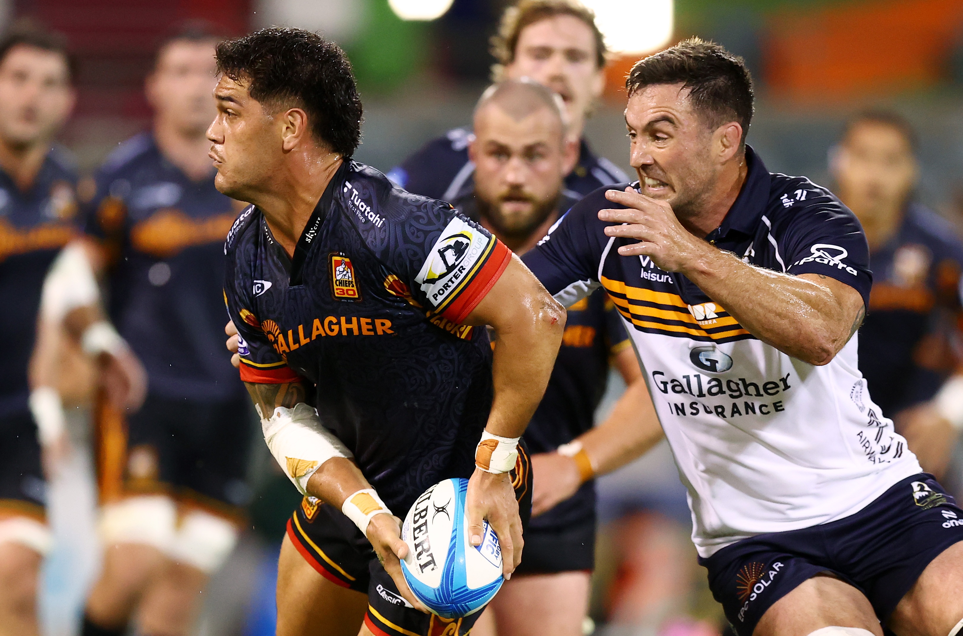 Quinn Tupaea of the Chiefs looks to pass the ball while the Brumbies' Caderyn Neville attempts a tackle.