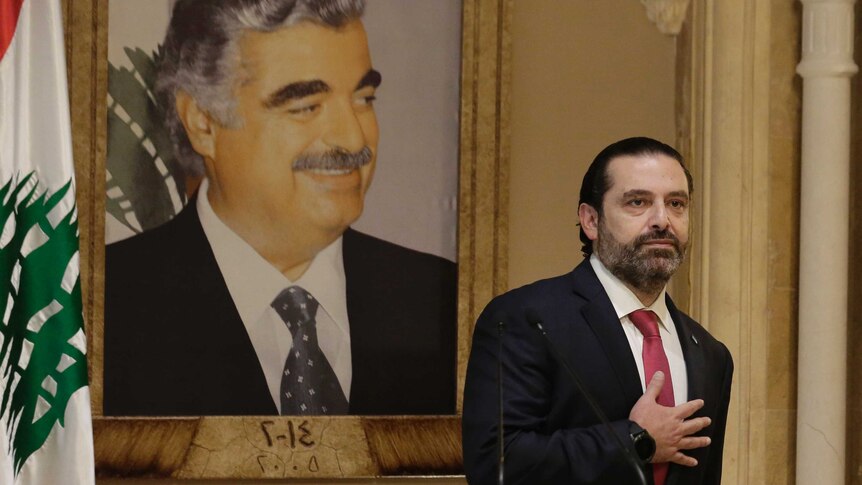 Lebanese Prime Minister Saad Hariri stands near a Lebanese flag holding his hand on his heart.