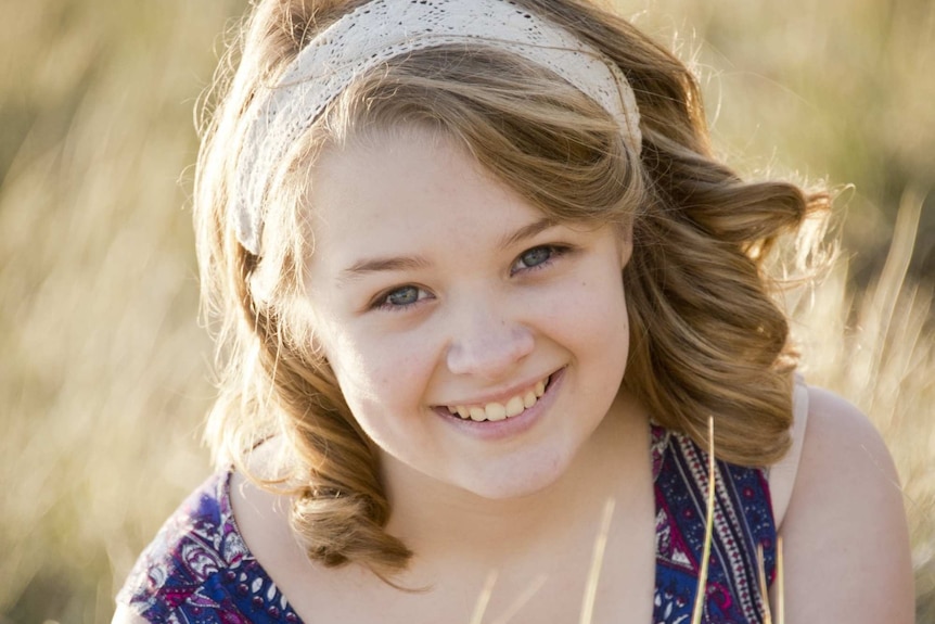 A young teenage girl smiling in a field