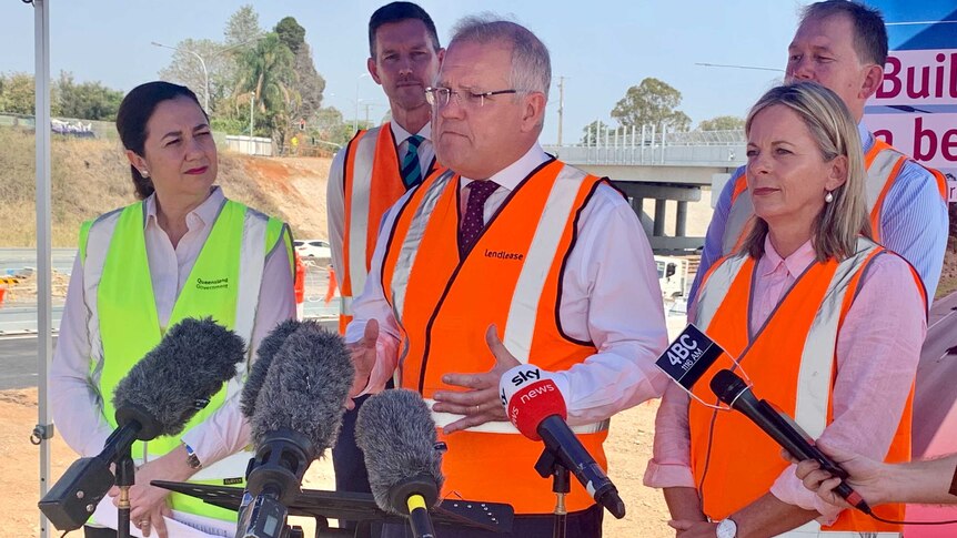 The Prime Minister in a high viz vest speaking to the media, with Queensland Premier Annastacia Palaszczuk standing next to him.