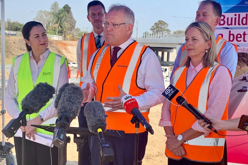 The Prime Minister in a high viz vest speaking to the media, with Queensland Premier Annastacia Palaszczuk standing next to him.