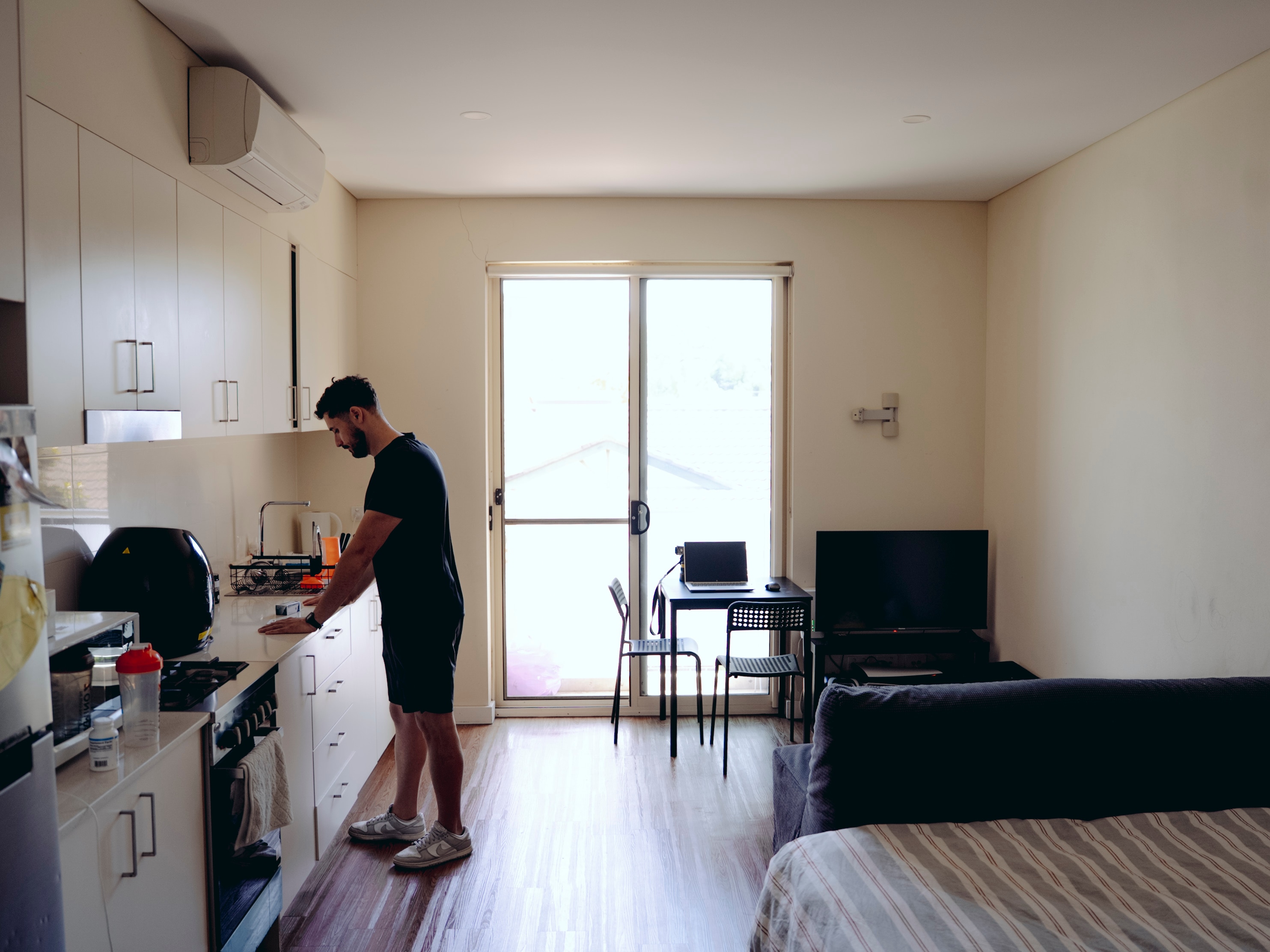 A wdie shot of Andre standing at his kitchen bench.