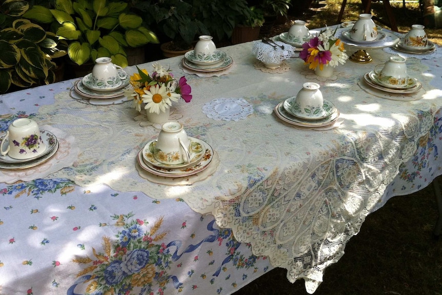 Table set with teacups, plates and lace table cloth for a garden party