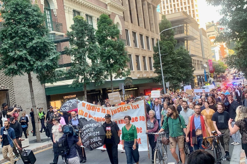 A large crowd walks through the Brisbane CBD.