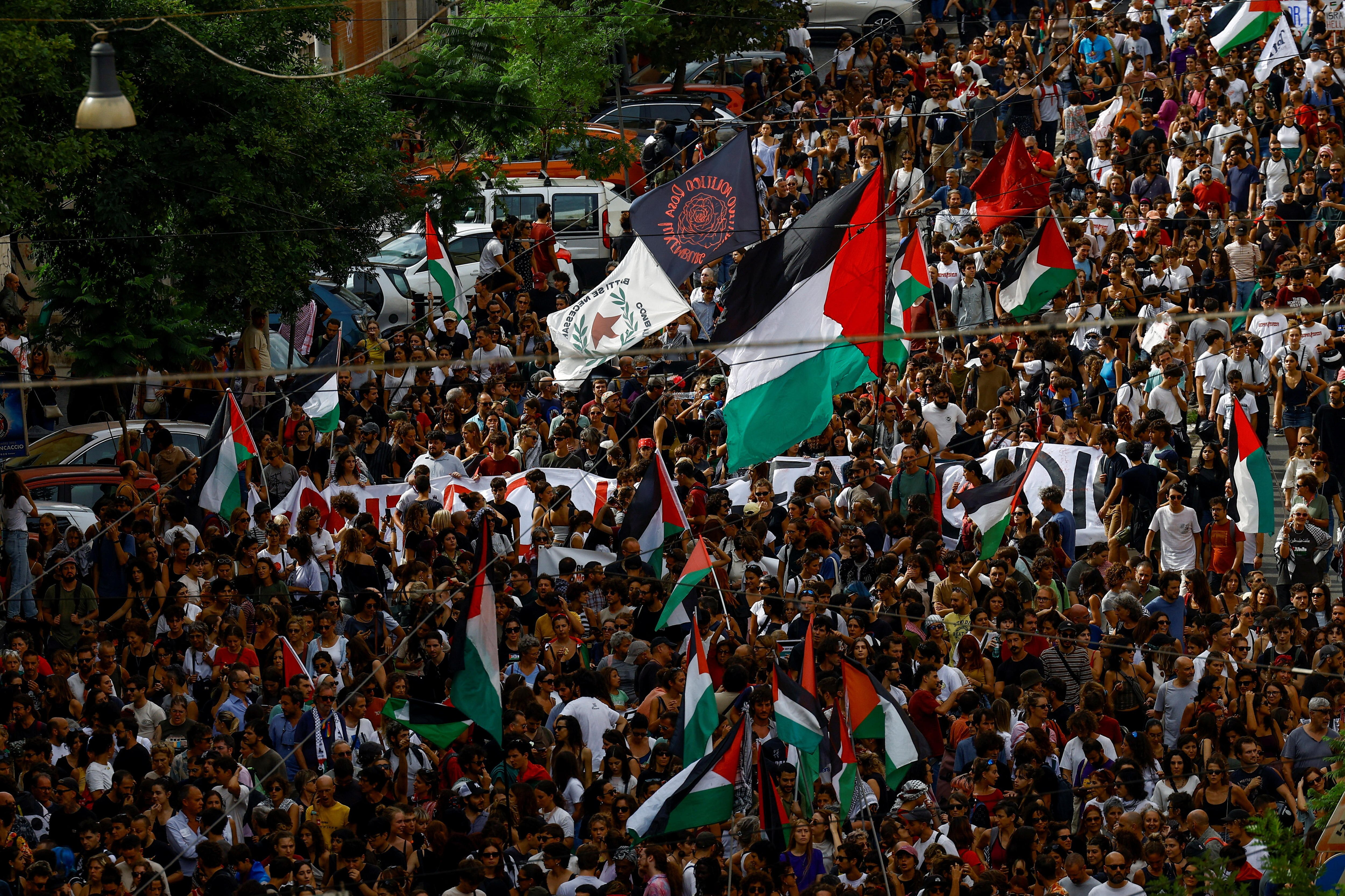 A large crowd holding Palestinian flags and banners walking down the street.