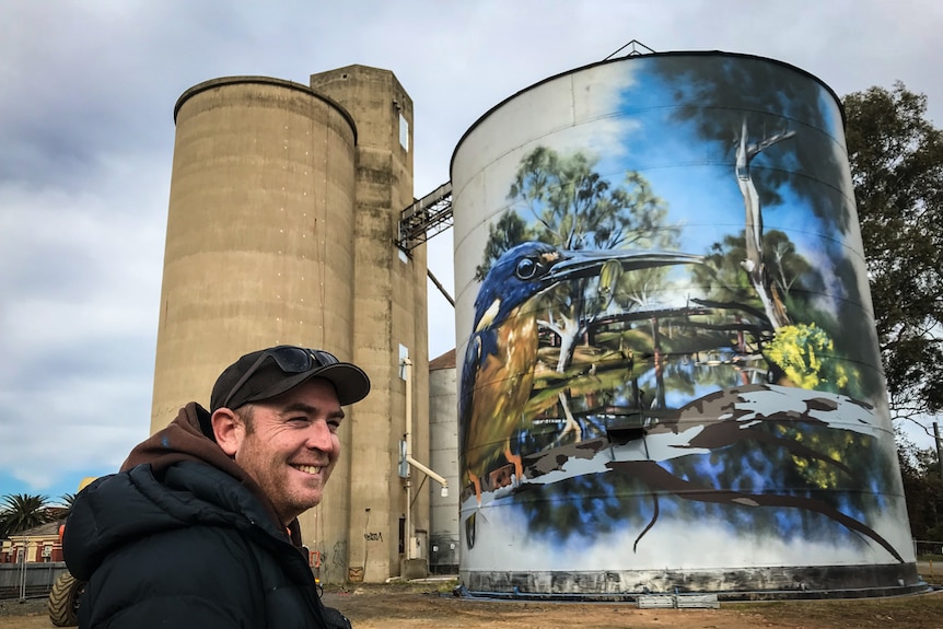 Artist Dvate faces his mural in Rochester. The right-hand-side silo is "90 per cent finished", he says.