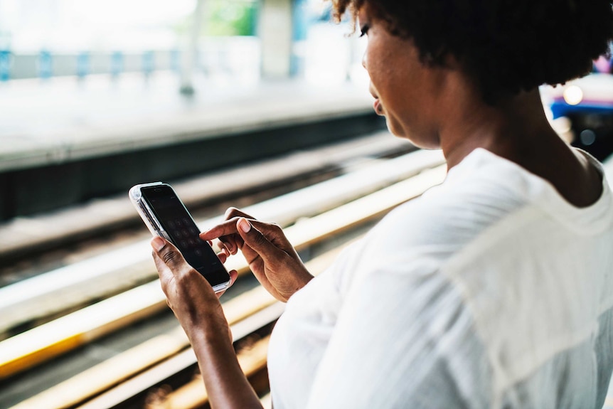 Woman looking at mobile phone while waiting for transport