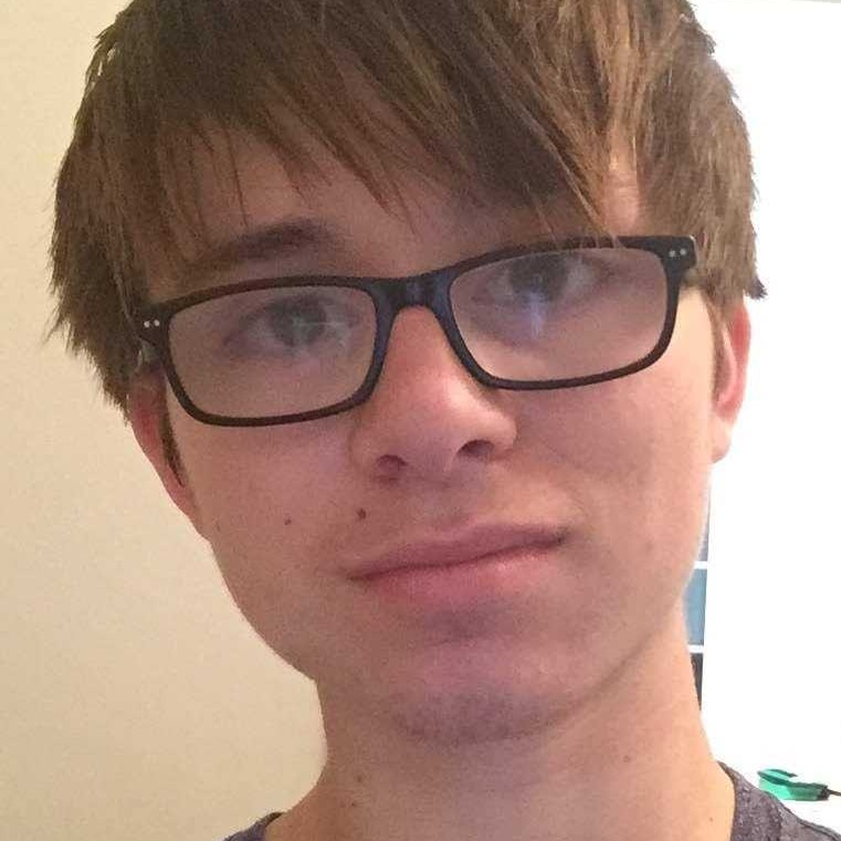 A young man with brown hair and black rimmed glasses 