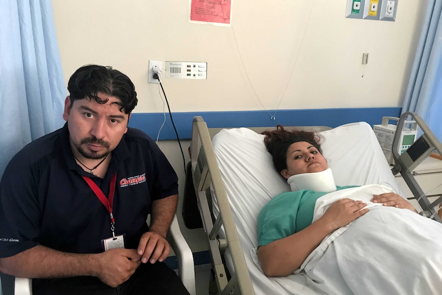 Juan Jesus Garcia comforts his wife Diana as she lay in a hospital bed wearing a neck brace.