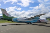 A white Air Vanuatu plane with green and blue design on a tarmac. 