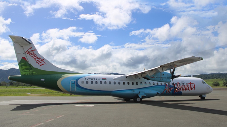 A white Air Vanuatu plane with green and blue design on a tarmac. 