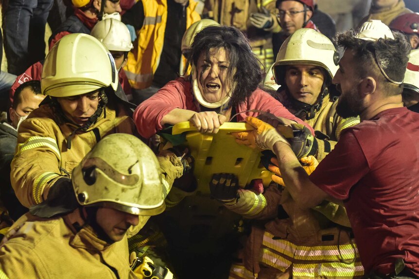 A woman reacts after rescue workers had pulled her out the rubble of an eight-story building which collapsed in Istanbul.