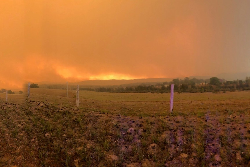 fire front over ridgeline and thick black sky