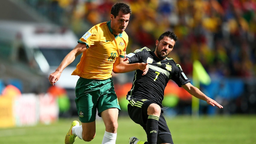 Australia's Ryan McGowan is challenged by Spain's David Villa during the 2014 World Cup.
