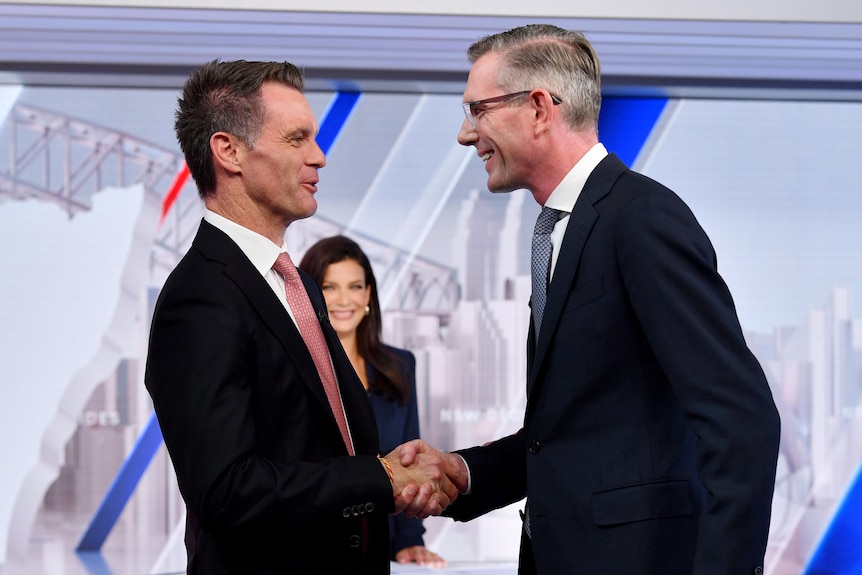 Chris Minns and Dominic Perrotet shake hands in a TV studio after an election debate.